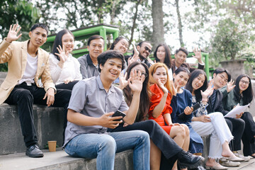 Group of business people sitting outside and waving hand to the camera