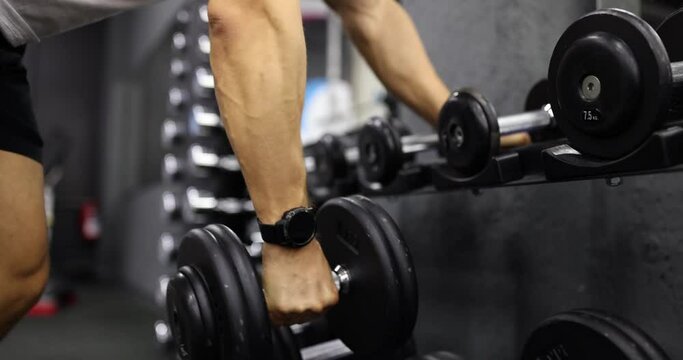 Male hands take dumbbells for bodybuilding in gym. Closeup sportsman hands taking weight lifting in sport club