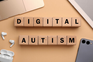 Phrase Digital Autism made of wooden cubes and devices on beige background, flat lay. Addictive...