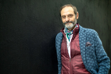 Senior man leaning on a black wall looking at camera. photo with copy space