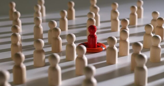 One red figure in life buoy between wooden figurines of people. Individuality, uniqueness, leadership and saving people