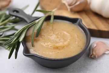 Delicious turkey gravy, rosemary and garlic on light grey table, closeup