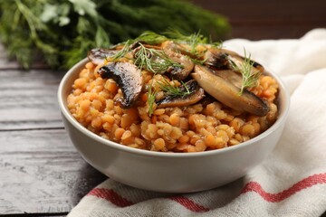 Delicious red lentils with mushrooms and dill in bowl on table, closeup