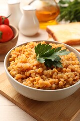Delicious red lentils with parsley in bowl served on table, closeup