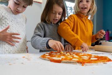 Children cooking homemade pizza together