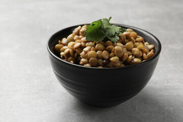 Delicious lentils with parsley in bowl on light grey table, closeup