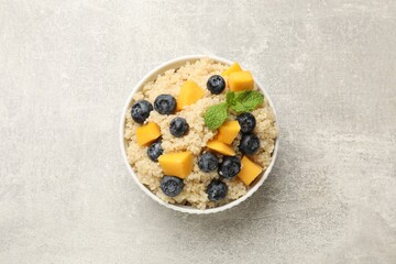 Tasty quinoa porridge with blueberries and pumpkin in bowl on light grey table, top view