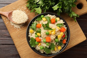 Tasty quinoa porridge with vegetables in bowl on wooden table, flat lay
