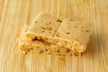 Turron blocks with almonds and hazelnuts on chopping board, on wooden table.