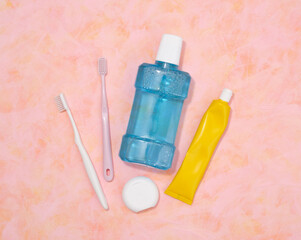Blue mouthwash, yellow tube of toothpaste, floss and toothbrushes. Flat lay, dental concept.