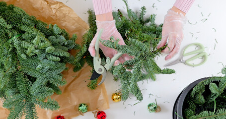 Women making Christmas wreath using pine branches and festive decorations