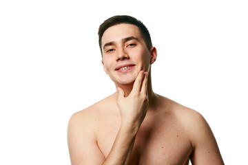 Naklejka premium Handsome man, well-groomed guy with bare shoulders smiling and touching chin looking at camera against white background. Concept of beauty treatment and hygiene, body care, anti-aging procedures.
