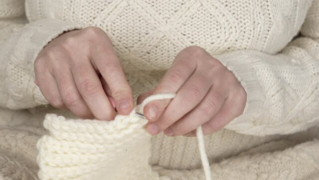 Crochet close-up. Women's hands knit a white product with a pink crochet with thick woolen threads. Handicrafts, handicrafts, hobbies.
