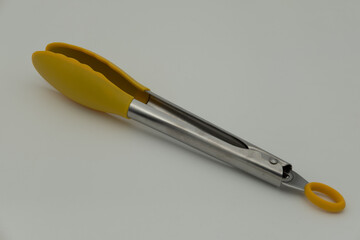 Yellow cooking tongs on a white background
