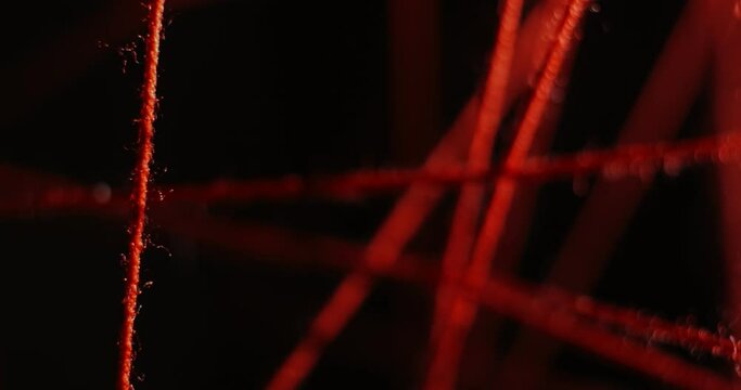 Stretched red threads in different directions and planes on a black background. Solving a crime