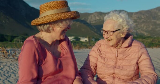 Senior women, happy and conversation on beach, bonding and laughing or relaxing on holiday. Elderly friends, care and humor in nature for support in retirement, funny joke and talking in outdoors