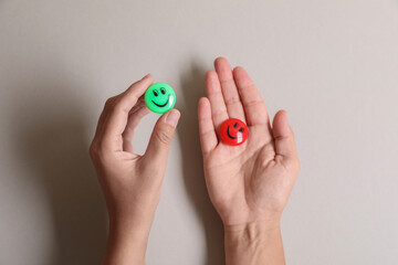 Choice concept. Woman holding magnets with happy emoticons on light background, closeup