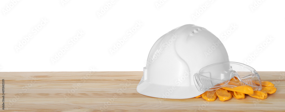 Poster Hard hat, gloves and goggles on wooden table against white background. Safety equipment