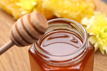 Sweet honey in jar and dipper on table, closeup