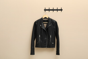 Hanger with black leather jacket on beige wall