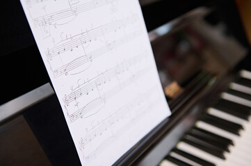 Still life shot. Cropped View of old vintage classical wooden piano and music notes on white paper...