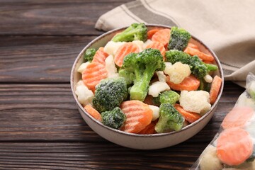 Mix of different frozen vegetables in bowl on wooden table, closeup. Space for text