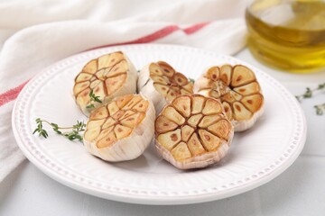 Heads of fried garlic and thyme on white table, closeup