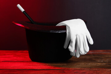 Black top hat, gloves and wand on wooden table. Magician equipment