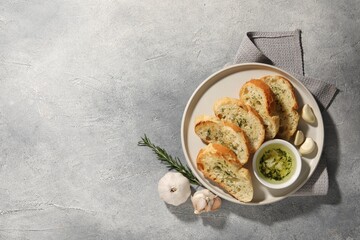Tasty baguette with garlic and dill served on grey textured table, top view. Space for text