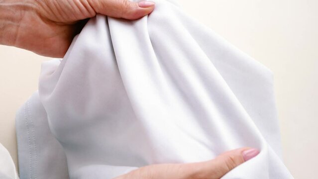 Clean clothes. Female hands touching a snow-white T-shirt