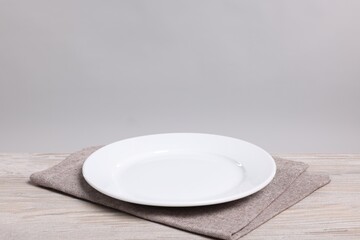 Empty ceramic plate on wooden table against light background, space for text © New Africa