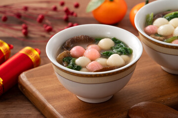 Eating red and white small tangyuan with savory soup and vegetable for lunar new year festival.
