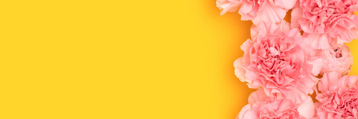 Banner with pink carnation and rose flowers on a yellow background. Selective focus.
