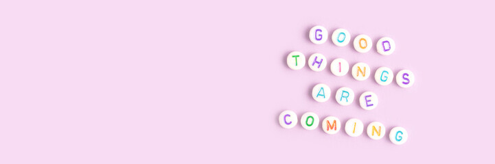 Good things are coming. Banner with quote made of round beads with letters on a purple background....