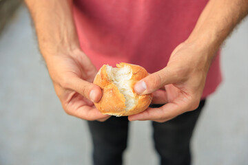 A man's hand holds a round bun, snack and fast food concept. Selective focus on hands with blurred background