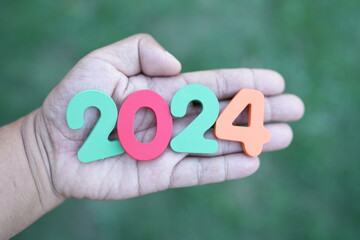 Happy New Year 2024 concept, wooden numbers 2024 in human hand