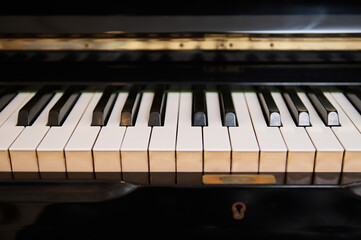 Close-up front view of classic grand piano keyboard. Ebony and ivory piano keys. Chord musical...