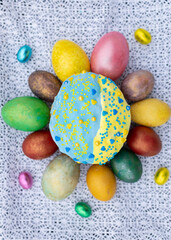 Happy Easter. A delicious freshly baked Easter cake glazed with yellow and blue icing around which lie multi-colored eggs and mini-egg candies on lace. sweet table for the Orthodox holiday of Easter