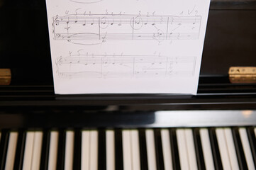 Close-up of white paper sheet with musical notes on old piano