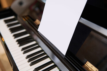 Close-up shot of classical piano and white paper sheet with music notes for performing musical...