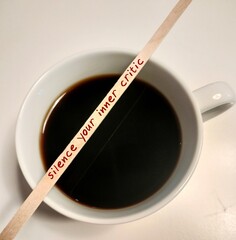 Stirer on coffee cup with text written Silence Your Inner Critic - self talk to tame negative inner...
