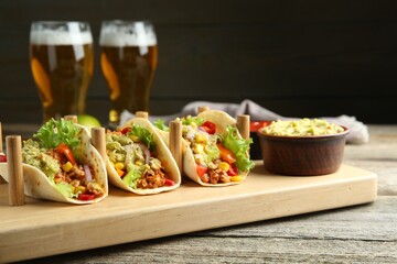 Delicious tacos with guacamole, meat and vegetables served on wooden table