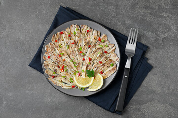 Tasty pickled anchovies with spices and fork on grey textured table, top view