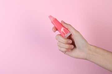 Woman with lip balm on pink background, closeup
