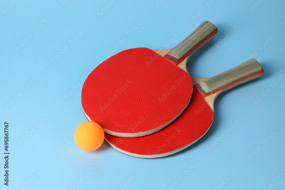 Wall mural Ping pong ball and rackets on light blue background