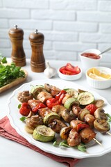 Delicious shish kebabs with vegetables and microgreens served on table, closeup