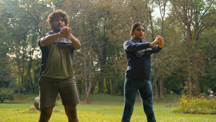 Active sporty two couple doing squats workout exercise in park nature outdoors sport together...