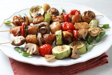 Delicious shish kebabs with vegetables and microgreens on table, closeup