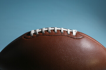 American football ball on light blue background, closeup