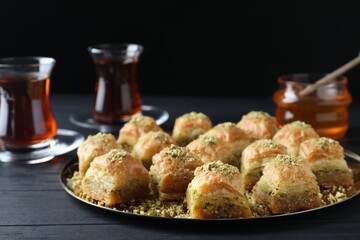 Delicious fresh baklava with chopped nuts on black wooden table. Eastern sweets